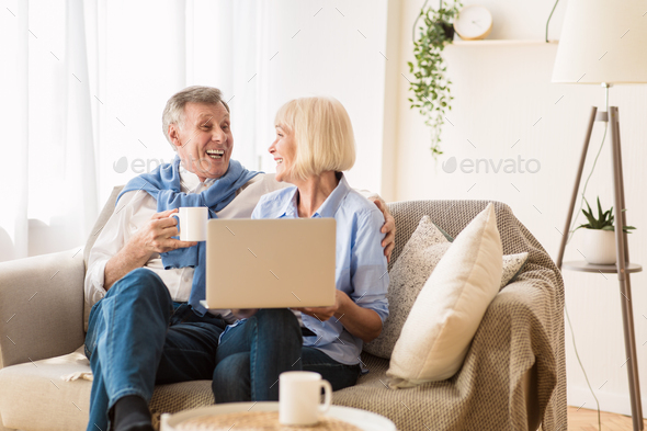 Happy mature couple watching comedy film on laptop