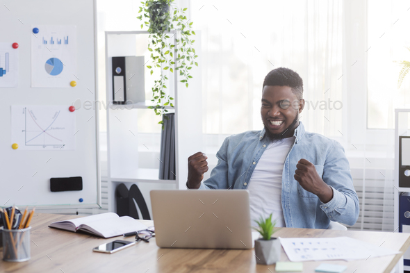 Ecstatic African American Employee Rejoicing Business Success At Workplace In Office