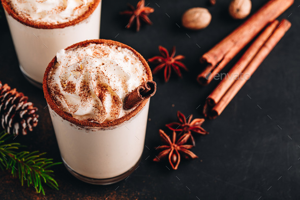 Traditional Christmas drink Eggnog with whipped cream and cinnamon on dark stone background. - Stock Photo - Images