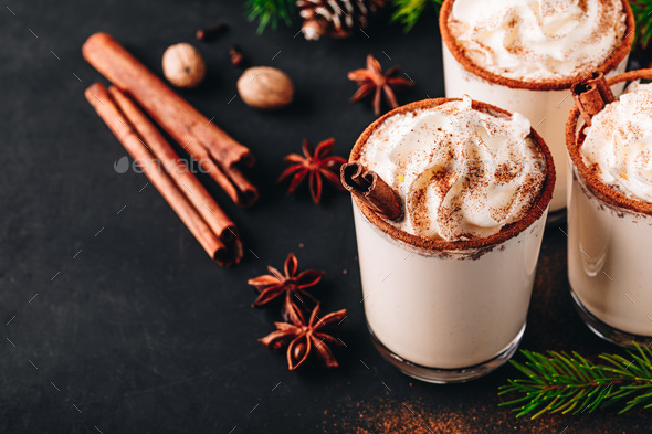 Traditional Christmas drink Eggnog with whipped cream and cinnamon on dark stone background. - Stock Photo - Images