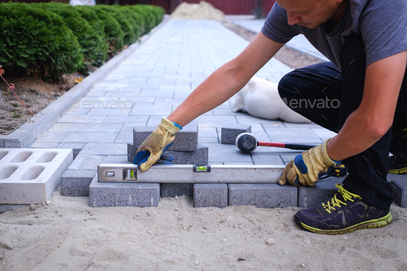 The master in yellow gloves lays paving stones - Stock Photo - Images