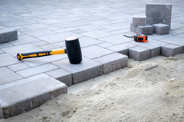 The master in yellow gloves lays paving stones - Stock Photo - Images