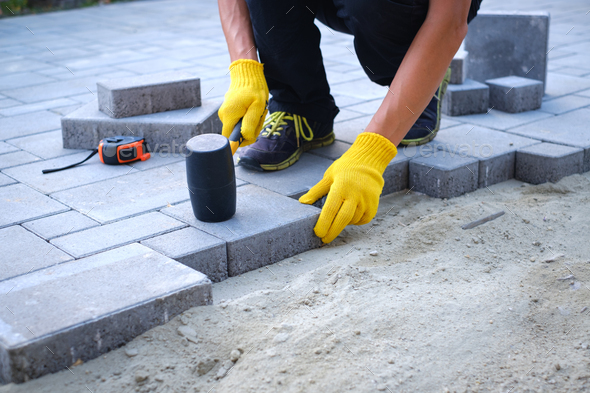 The master in yellow gloves lays paving stones - Stock Photo - Images