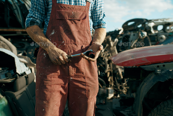 Male mechanic in welding glasses on car junkyard