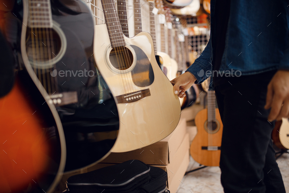 Customer choosing acoustic guitar in music store