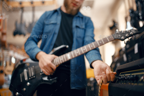 Guitarist plays on electric guitar in music store