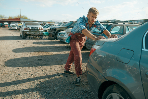 Male mechanic pushing the car on junkyard - Stock Photo - Images