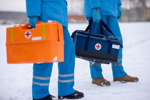 Low section of young paramedics with first aid kits ready to save sick people