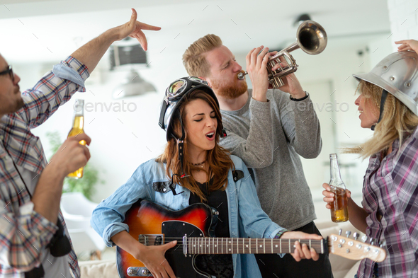 Cheerful friends having party together and playing instruments