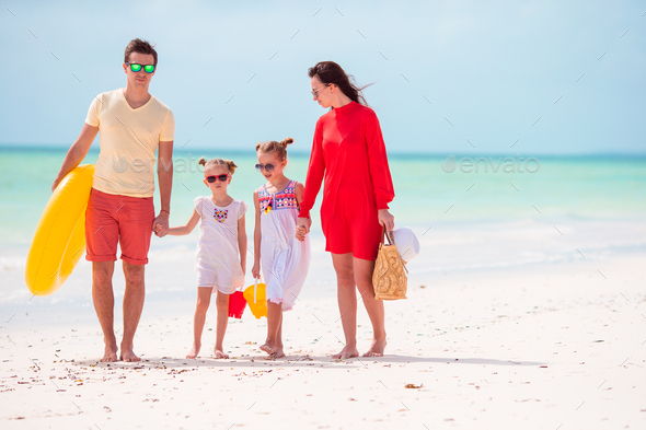 Family of four on beach vacation with inflatable ring and toy buckets ...