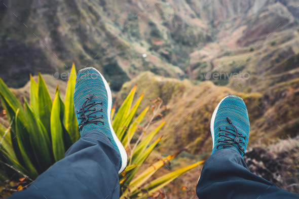 Feet of traveler streching down his legs over breathtaking mountain landscape with mountain peaks - Stock Photo - Images
