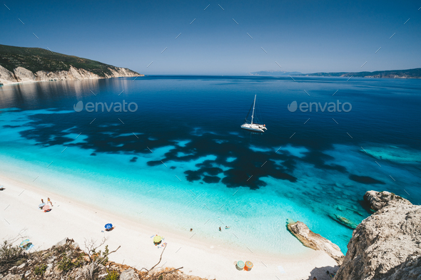 Beach leisure activity. Fteri bay, Kefalonia, Greece. White catamaran yacht in clear blue sea water - Stock Photo - Images
