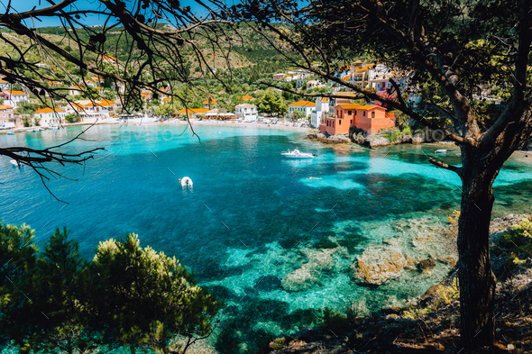 View on tourquise transparent bay of mediterranean village Assos framed through green pine grove - Stock Photo - Images