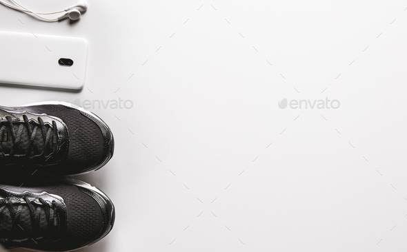 Mockup mobile cellphone with earphone and running shoes on white background. Healthy lifestyles