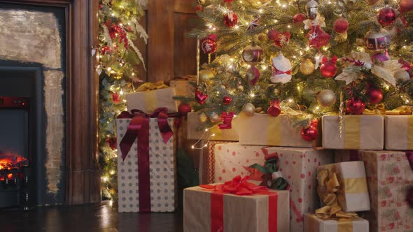 Christmas Gifts Under Decorated Tree in Dark Room Illuminated with Fire From Fireplace alt