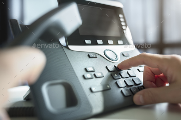 Dialing a telephone in the office - Stock Photo - Images