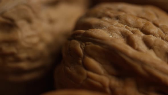 Cinematic, rotating shot of walnuts in their shells on a white surface - WALNUTS  alt