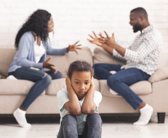 Upset black girl closing ears for not listening parents arguing