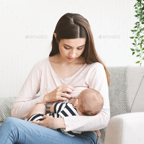 Young mother feeding her newborn child with breast milk Stock