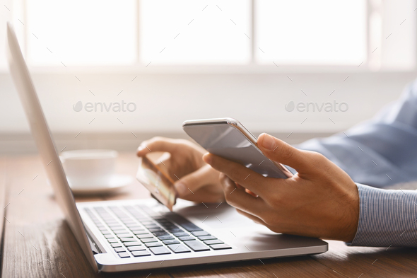 Unrecognizable businessman booking tickets online using smartphone and credit card - Stock Photo - Images