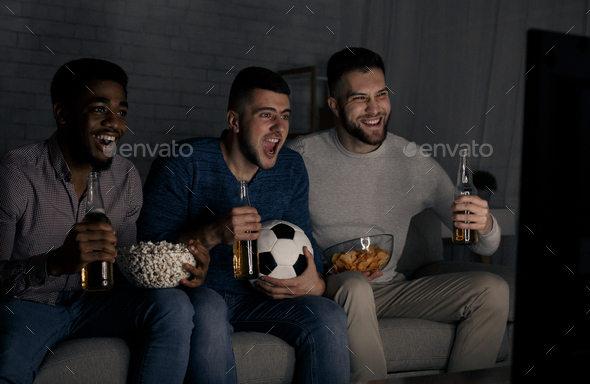 Diverse men watching football match at home