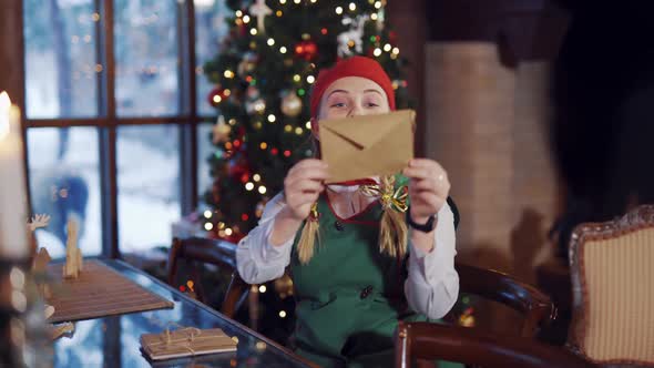 Cute elf with envelope on the background of Christmas lights. alt