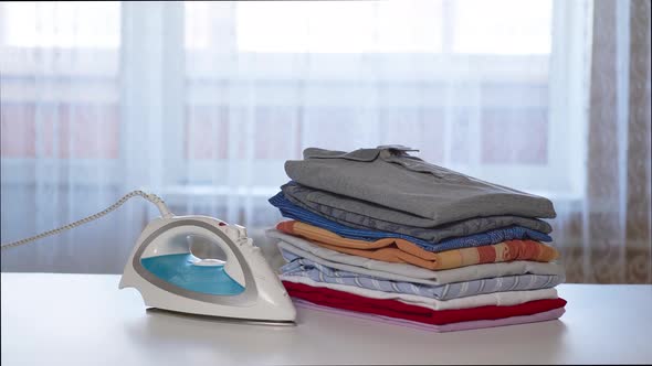 Iron And A Stack Of Clean Clothes On An Ironing Board