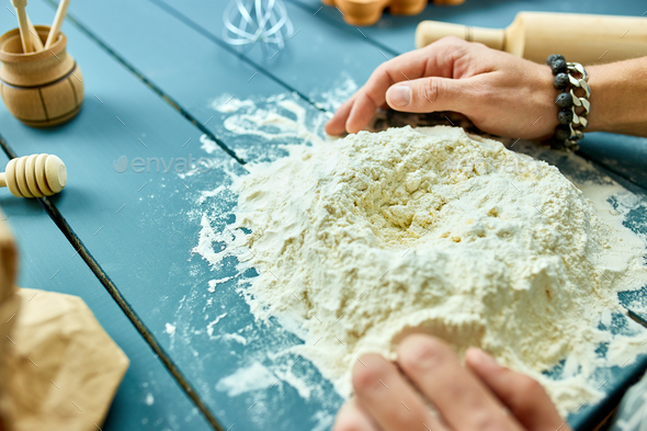 Man forming the dough on a floured surface and kneading it with his hands. - Stock Photo - Images