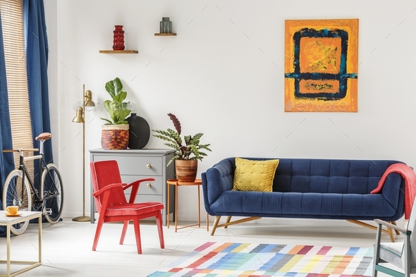 Red chair and royal blue lounge placed in bright sitting room in - Stock Photo - Images