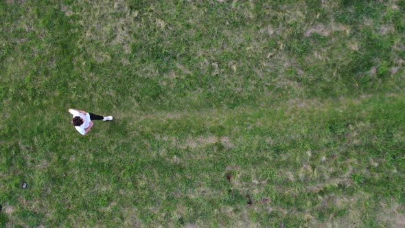 Birds Eye Aerial View of Drone Flying Above Male Runner on Green Meadow in Park. Top Down Static Sho alt
