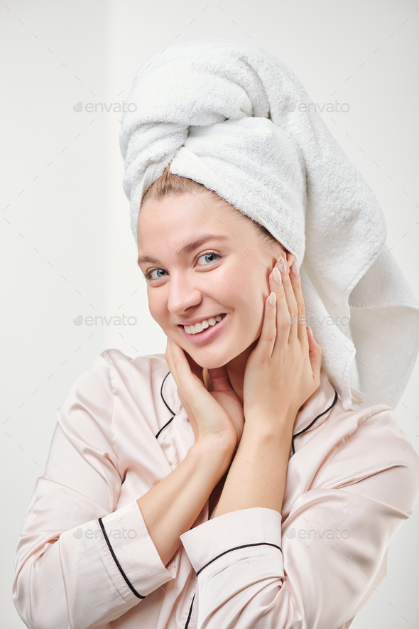 Healthy young woman with toothy smile touching her clean hydrated radiant face