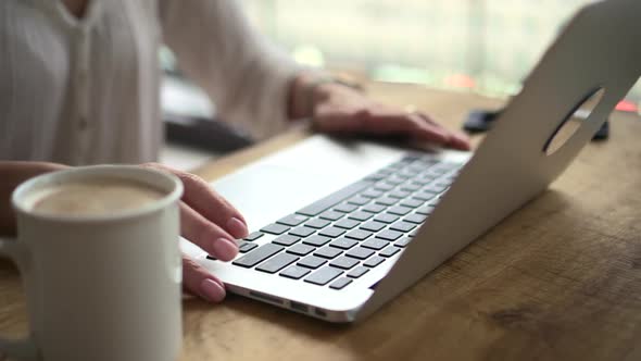 Businesswoman Typing on Laptop Keyboard and Sitting at Table in Home Office alt