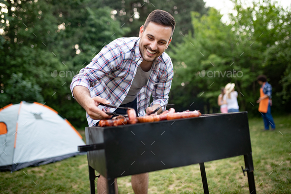 Man cooking meat on barbecue grill at outdoor summer party