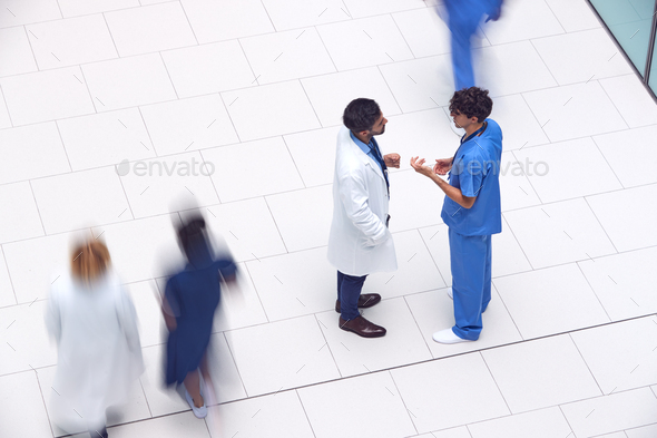 Overhead View Of Male Medical Staff Having Informal Meeting In Lobby Of Modern Hospital Building
