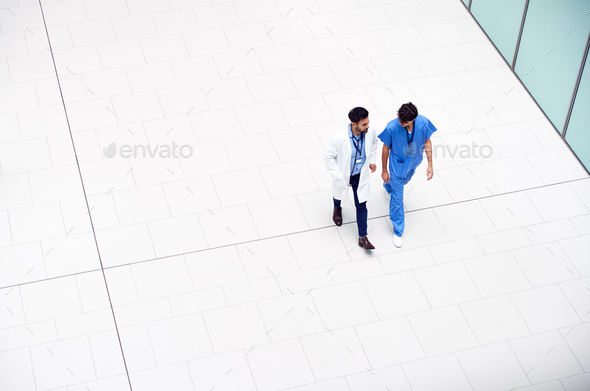 Overhead View Of Medical Staff Talking As They Walk Through Lobby Of Modern Hospital Building