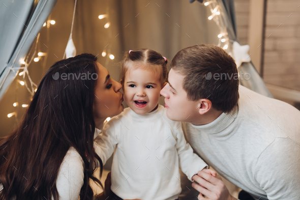 Loving parents kissing their cute daughter in cheeks - Stock Photo - Images