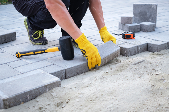 The master in yellow gloves lays paving stones - Stock Photo - Images