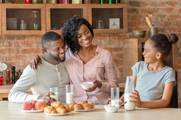 Adorable black family of three having breakfast at kitchen