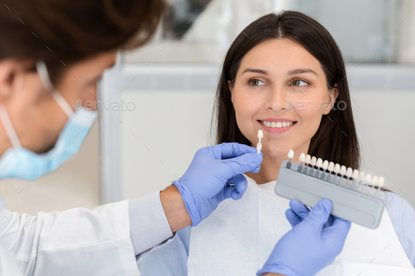Dentist applying sample from tooth scale to smiling patient teeth