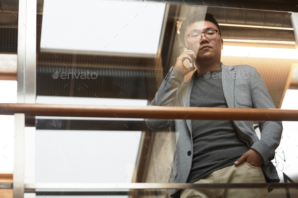 Asian Businessman Speaking by Smartphone Low Angle - Stock Photo - Images
