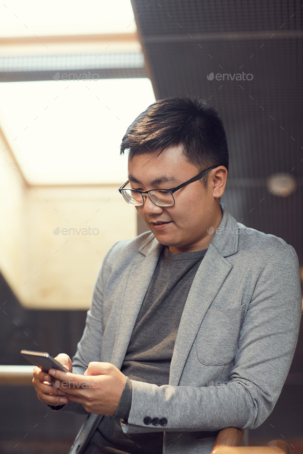 Young Asian Businessman using Smartphone in Office