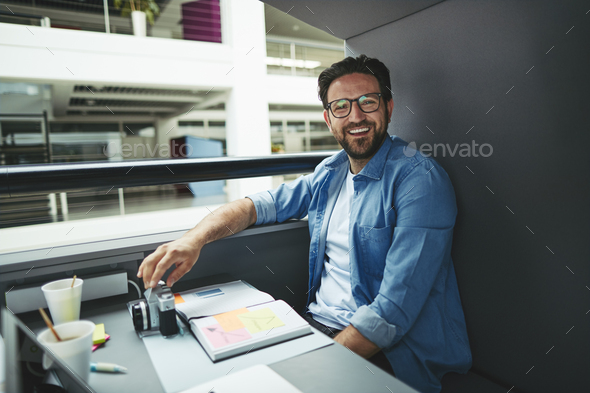 Laughing designer working inside of an office meeting pod
