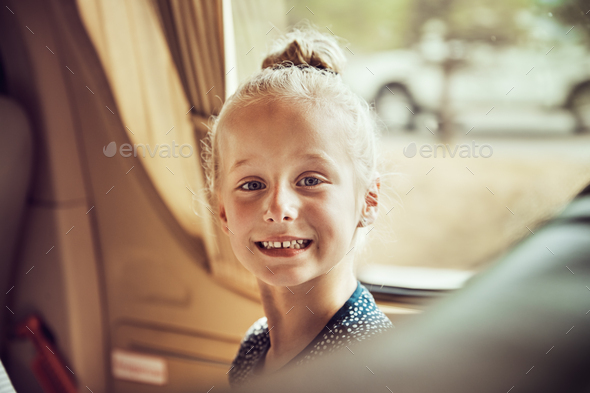 Cute little girl smiling while sitting in a car