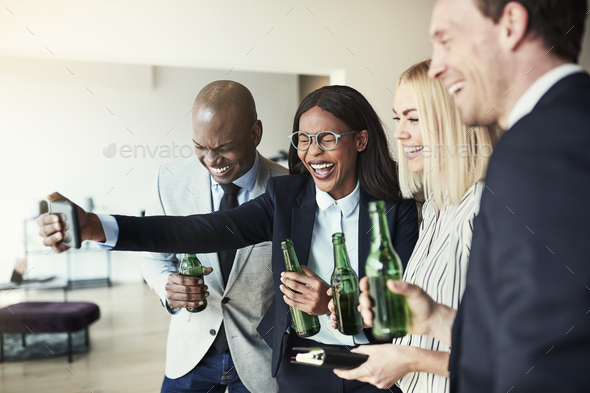 Laughing businesswoman taking selfies over drinks with colleagues after work - Stock Photo - Images