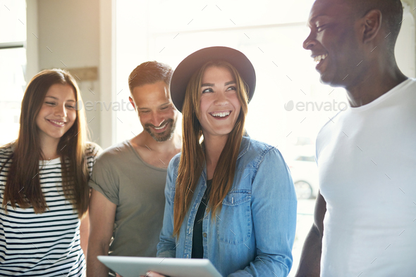 Four diverse happy adults looking at tablet - Stock Photo - Images