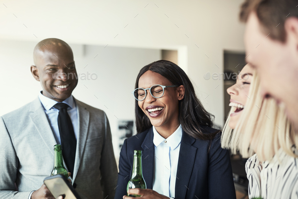 Diverse group of laughing businesspeople having drinks in an office - Stock Photo - Images