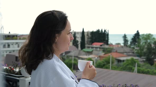 Young Female Drinking Coffee on a Hotel Balcony alt