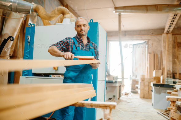 Carpenter processes board on plane machine - Stock Photo - Images