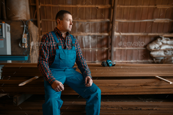 Joiner in uniform at his workplace on timber mill - Stock Photo - Images