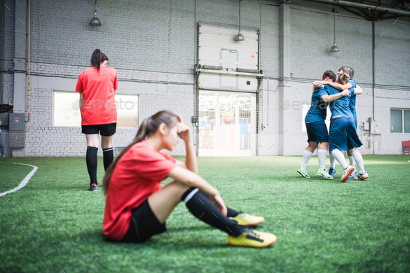 Upset girls in red sports uniform and happy young females in blue sportswear - Stock Photo - Images